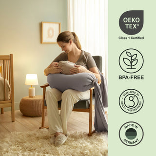 Woman holding a baby wrapped in a blanket with Oeko-Tex, BPA-Free, and Made in Germany certification logos on the right bbhugme pregnancy pillow